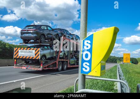 Itatiba-sp,brasile-aprile 19,2023 Telefono su autostrada utilizzato per le emergenze con il segnale universale di s.o.s e un camion con le automobili che passano sul high Foto Stock