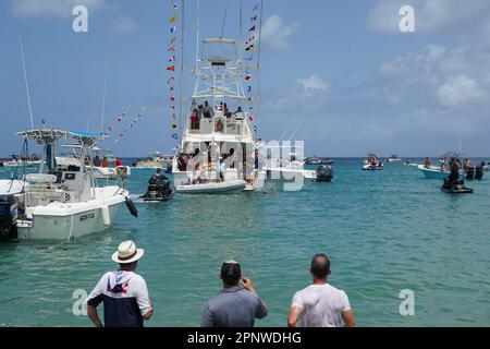 Una barca porta una statua della Vergine del Carmen (Vergine del Monte Carmelo), considerata il santo patrono dei pescatori, durante una processione annuale ad Aguadilla, Porto Rico, il 17 luglio 2022. La processione inizia con sacerdoti e adoratori che camminano e cantano a terra fino a raggiungere la spiaggia, dove centinaia di barche aspettano per continuare verso il mare. (Coraly Cruz Mejías/Global Press Journal) Foto Stock