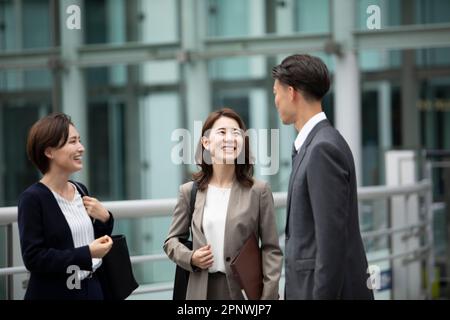 Due uomini d'affari e una donna d'affari che camminano nella conversazione. Foto Stock