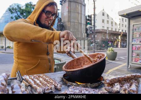 Emanuel Nemmi stimola le arachidi caramellate a fare garrapiñadas al suo carrello di cibo a Buenos Aires, Argentina il 31 maggio 2022. Nemmi dice che essere un venditore di strada è imprevedibile, ma preferisce guadagnare soldi lui stesso invece di aspettare un assegno. (Lucila Pellettieri/Global Press Journal) Foto Stock