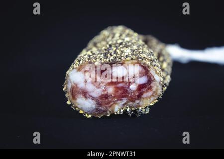 Immagine di una salsiccia di fuet affettata e rivestita in peppercorn. Il Fuet è un insaccato catalano di carne di maiale in un budello di maiale. Il più famoso è m Foto Stock