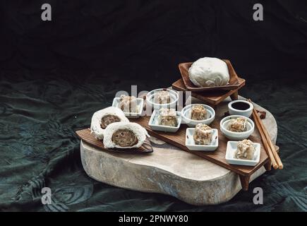 Panini al vapore con ripieno di maiale tritato e shumai di maiale o gnocchi di maiale cinese al vapore serviti con salsa aspre e bacchette di legno. Dim Sum. Cinese Spazio Foto Stock