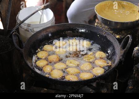 Friggere i kachori in una padella in una bancarella di cibo di strada, cibo oleoso Foto Stock