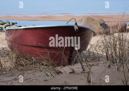 Solitaria barca da pesca rossa sulla spiaggia Foto Stock