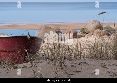 Solitaria barca da pesca rossa sulla spiaggia Foto Stock