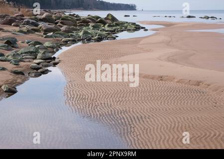 Pietre verdi sulla spiaggia vuota, ornamento d'onda nella sabbia Foto Stock