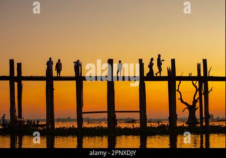 Amarapura, Myanmar - 22 novembre 2016: Persone non identificate camminano sul ponte U Bein al tramonto in Myanmar. Il ponte U Bein è il ponte in teak più lungo del Th Foto Stock