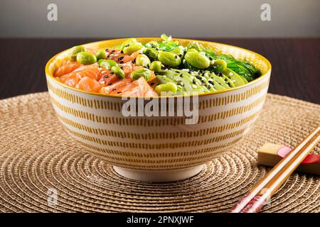 Appetitosa e salutare ciotola di poke con salmone e verdure servite con semi di sesamo e bastoncini di carne sul tavolo Foto Stock