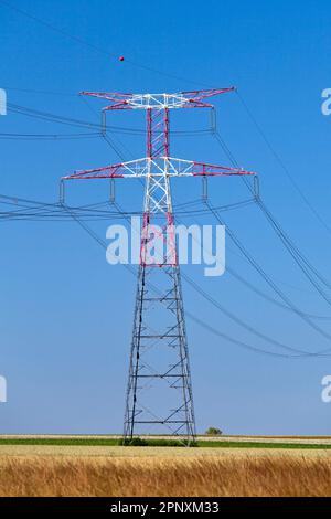 Piloni elettrici nella campagna francese sotto un cielo blu chiaro. Foto Stock