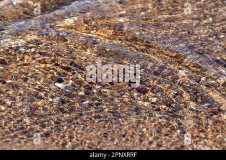 Acqua chiara e poco profonda increspata su sabbia ciottolosa Foto Stock