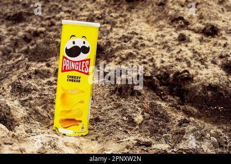 Pringles patatine fritte con formaggio in un pacchetto giallo sono stati presi in un cortile privato il 19 aprile 2023 in Ucraina sullo sfondo di sabbia Foto Stock