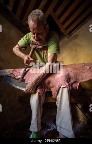 Un operaio nelle concerie di Fez ammorbidisce le pelli già conciate con un attrezzo speciale che viene spinto con il petto. Foto Stock