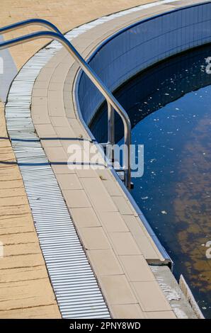 bordo di una piscina abbandonata con acqua sporca Foto Stock