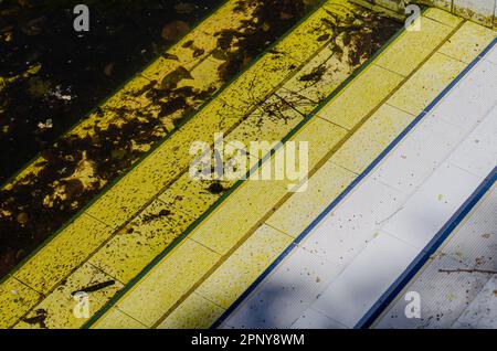 bordo di una piscina abbandonata con acqua sporca Foto Stock