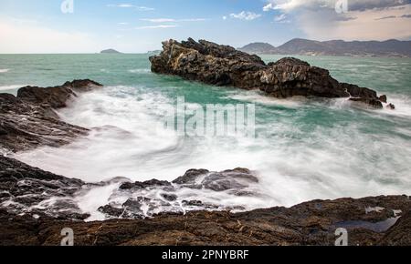 Onde che scorrono intorno alle rocce costiere del mare Foto Stock