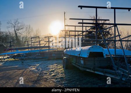 Un'alba invernale misteriosa e sorprendentemente bella scoppia da dietro gli alberi sulle rive del Tamigi da Radley College Boathouse su un Wi ghiacciato Foto Stock