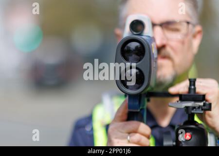 Norimberga, Germania. 21st Apr, 2023. L'ispettore capo Dirk Klinge, capo del dipartimento di polizia stradale di Norimberga, guarda attraverso un dispositivo di misurazione laser portatile (pistola laser) del tipo LTI 2020 Truespeed durante la cosiddetta maratona di velocità. In circa 1800 punti di misurazione in tutta la Baviera, la polizia e i dipendenti dei comuni, nonché del controllo del traffico municipale, vigilano sui velocisti. Soprattutto, tuttavia, vengono effettuati controlli anche quando il rischio di incidenti causati dalla velocità è maggiore o quando la velocità è frequente. Credit: Daniel Karmann/dpa/Alamy Live News Foto Stock