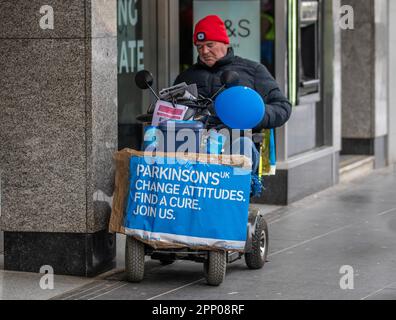 'Change Attitudes, Find Cure'  mese di consapevolezza del Parkinson Aprile 2023; uomo disabile in sedia a rotelle a motore raccolta per la ricerca a Southport, Merseyside, Regno Unito Foto Stock