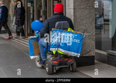 'Change Attitudes, Find Cure'  mese di consapevolezza del Parkinson Aprile 2023; uomo disabile in sedia a rotelle a motore raccolta per la ricerca a Southport, Merseyside, Regno Unito Foto Stock