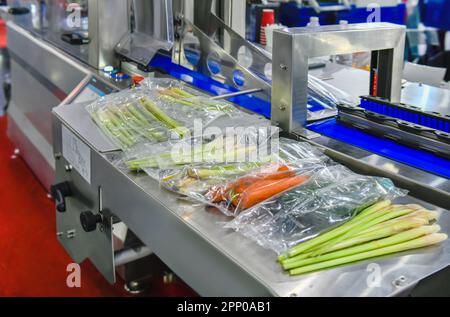 Ortaggi freschi confezionati in una linea di produzione di sacchetti di plastica trasparente in fabbrica, produzione alimentare industriale Foto Stock