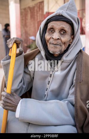 Ritratto di un vecchio vestito con abiti tradizionali, appoggiato su una canna. Foto Stock