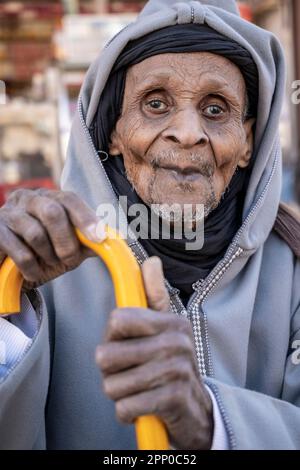 Ritratto di un vecchio vestito con abiti tradizionali, appoggiato su una canna. Foto Stock