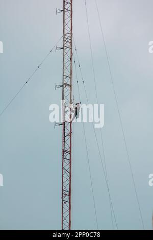 Gli uomini stanno salendo sull'antenna. Per installare il dispositivo Foto Stock