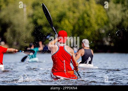 vista posteriore atleti di gruppo kayak in kayak singolo remi di allenamento sul lago, spruzzi e gocce d'acqua dalle pagaie Foto Stock