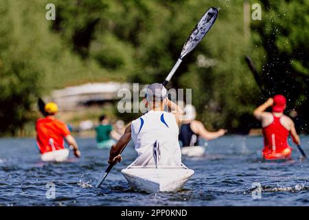 vista posteriore atleti di gruppo kayak in kayak monotaia sul lago, sport estivi all'aperto Foto Stock