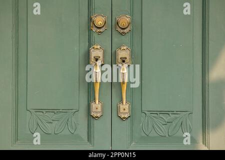 Maniglie delle portiere il vecchio ottone sulla porta verde era usato a. chiudere o aprire lo sportello Foto Stock