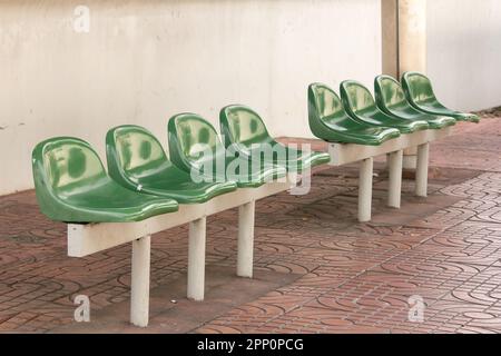 Sedia di plastica verde alla fermata dell'autobus per i passeggeri in attesa Foto Stock