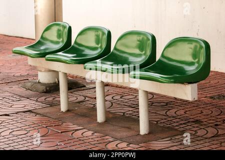 Sedia di plastica verde alla fermata dell'autobus per i passeggeri in attesa Foto Stock