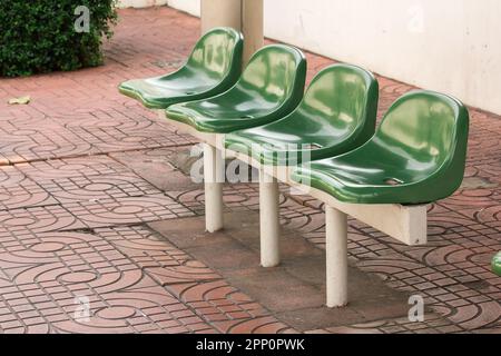 Sedia di plastica verde alla fermata dell'autobus per i passeggeri in attesa Foto Stock