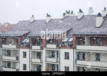 Neve bianca, grandi fiocchi di neve in caduta, vista del tetto dell'edificio con antenne montate e tubi di ventilazione contro il cielo grigio Foto Stock