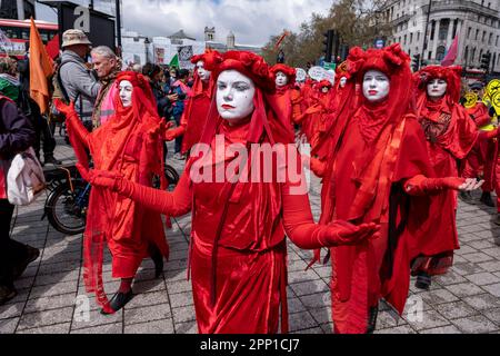 La brigata Red Rebel indossando costumi rossi luminosi marciano silenziosamente mentre migliaia di manifestanti di vari gruppi ambientalisti si uniscono alla ribellione di estinzione per la loro Unite a sopravvivere il giorno, parte della protesta non distruttiva di Westminster del 21st aprile 2023 a Londra, Regno Unito. Extinction Rebellion è un gruppo di cambiamento climatico iniziato nel 2018 e ha ottenuto un enorme seguito di persone impegnate in proteste pacifiche. Queste proteste stanno evidenziando che il governo non sta facendo abbastanza per evitare cambiamenti climatici catastrofici e per chiedere il Foto Stock