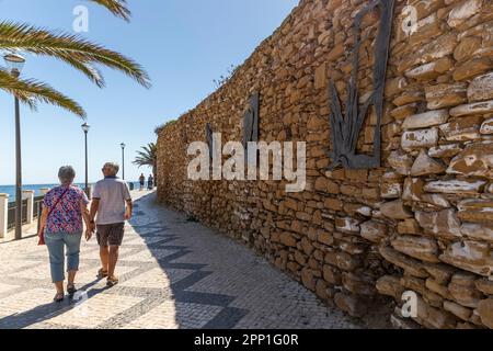 Coppia anziana a piedi sulla spiaggia di Luz vicino a Lagos nella regione dell'Algarve, Portogallo. Foto Stock