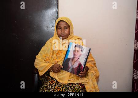 ReNu Begum (55) si pone per un ritratto con una foto del suo defunto figlio Robiul Islam Manik. Dieci anni fa, il 24th aprile 2013, il mondo è stato testimone di uno dei peggiori disastri industriali della storia, quando l'edificio di Rana Plaza in Bangladesh è crollato, uccidendo più di 1.100 persone e ferendo altre 2500 persone. La tragedia ha provocato ondate d'urto in tutto il mondo e ha suscitato preoccupazioni per le condizioni di lavoro non sicure del settore dell'abbigliamento pronto (RMG) in Bangladesh. L'edificio a otto piani ospitava diverse fabbriche che producevano abbigliamento per marchi globali come Primark, Mango e Benetton. L'buildin Foto Stock