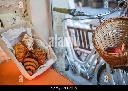 quattro tipi di croissant in un cestino su un tavolo bianco accanto alla finestra in un bar Foto Stock