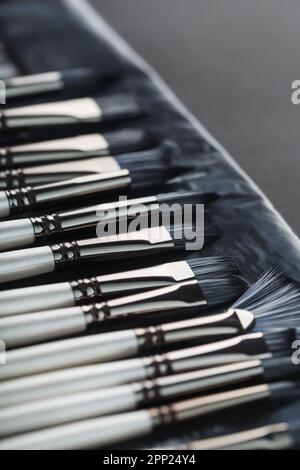 Tubi di verniciatura, pennelli per pittura e palette su vecchio sfondo in legno. Primo piano Foto Stock