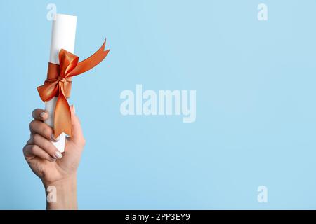 Donna in possesso di diploma con nastro su sfondo blu Foto Stock