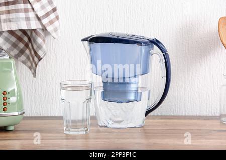 Caraffa filtro moderna e bicchiere d'acqua sul bancone della cucina Foto Stock