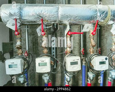 metri in un edificio residenziale, appartamenti per misurare l'energia termica. banconi con rubinetti rossi su un tubo metallico in lamina. fornendo le risorse per la residenza Foto Stock