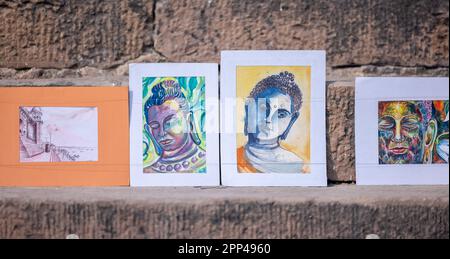 Dipinto del buddha fatto a mano su tela esposto sulle scale vicino al fiume gange a varanasi. Foto Stock