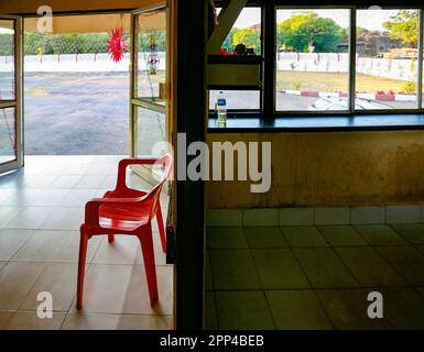 Sedia di plastica rossa vicino alla reception di un ristorante rurale presso l'autostrada in Maharashtra. Foto Stock