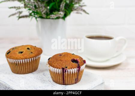 Cupcake con ribes nero e foglie di menta su un piatto bianco. Messa a fuoco selettiva. Foto Stock