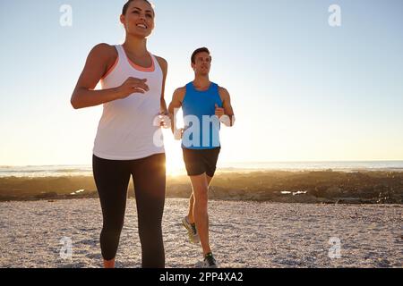 Ogni giorno è una nuova occasione per correre. una giovane coppia che fa jogging insieme sulla spiaggia. Foto Stock