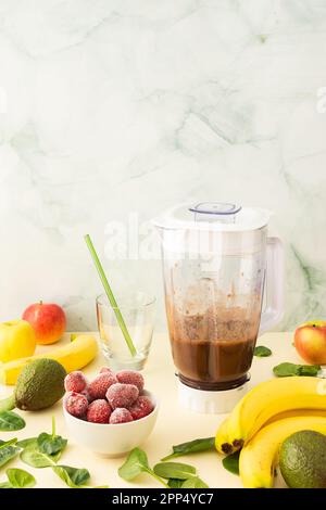 Colazioni salutari, frullati salutari e deliziosi con fragole e banane surgelate e avocado, proteina di piselli e verdure miste, frullato bicchiere mixer Foto Stock
