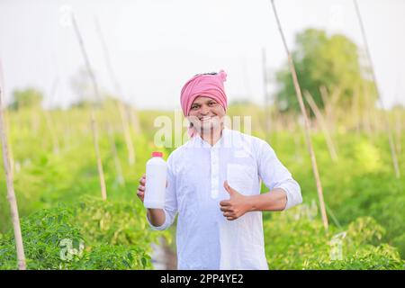 Giovane agricoltore indiano che mostra smartphone, agricoltore che parla al telefono in fattoria, agricoltore indiano felice Foto Stock