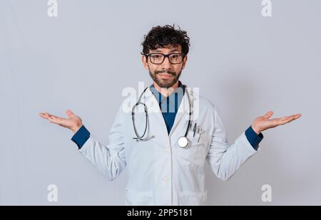 Dottore che presenta qualcosa con entrambe le palme. Giovane medico con palme aperte ai lati. Medico bearded con entrambe le palme aperte Foto Stock