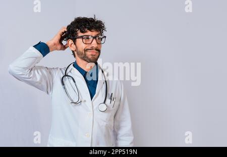 Medico confuso e premuroso isolato. Medico maschio graffiando la testa isolato. Medico premuroso che graffia la testa Foto Stock